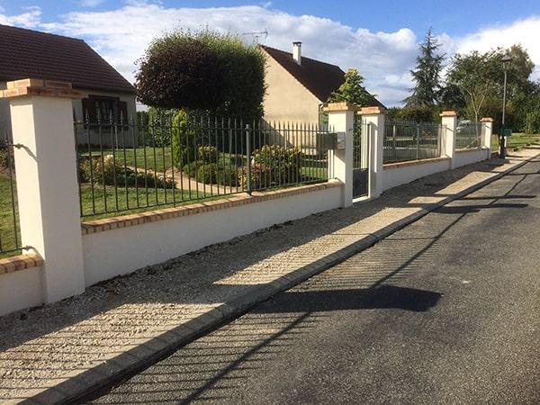 Fabrication et pose par scellement d'éléments de 3 mètres de clôture droite. Poteaux en tube scellés dans les chapeaux en brique. Intégration de la boite aux lettres et thermolaquage