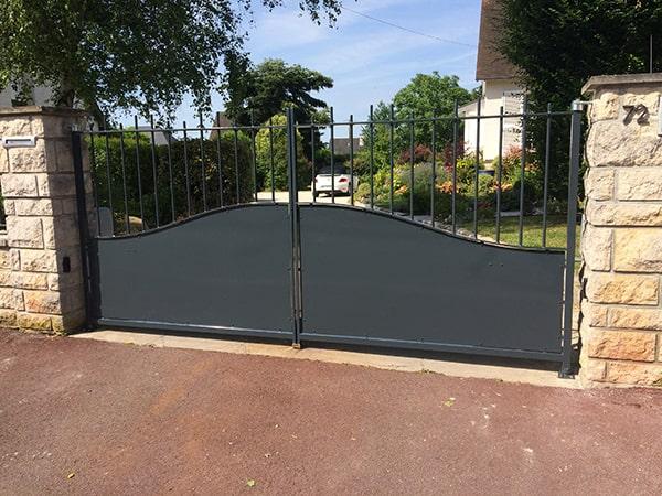 Portail acier avec sous bassement en chapeau de gendarme et barreaudage haut. Motorisation par bras compas CAME